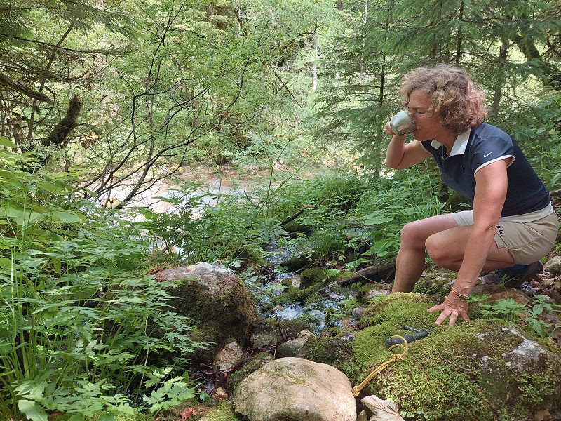 Ženska, ki pije vodo iz potoka