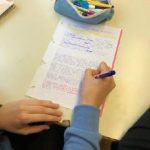 Fotografija roke, ki piše na list papirja