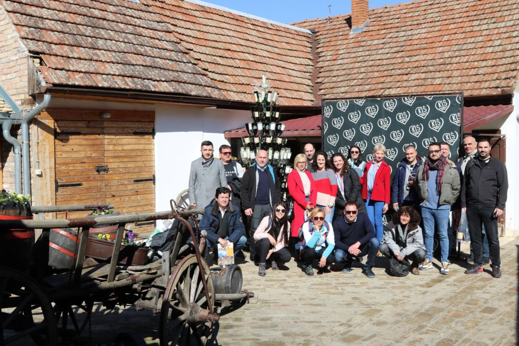 Skupina ljudi pred kmečkim poslopjem