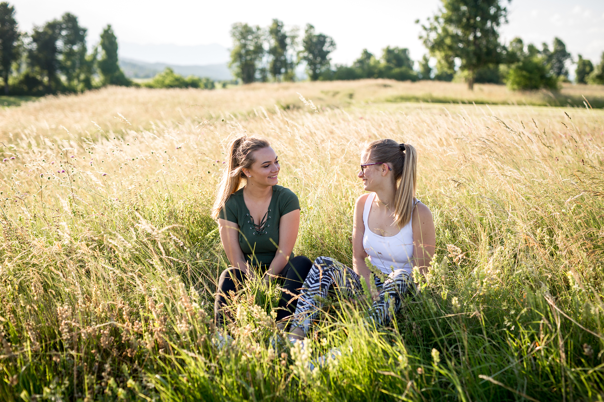 Dve dekleti sedita na travniku