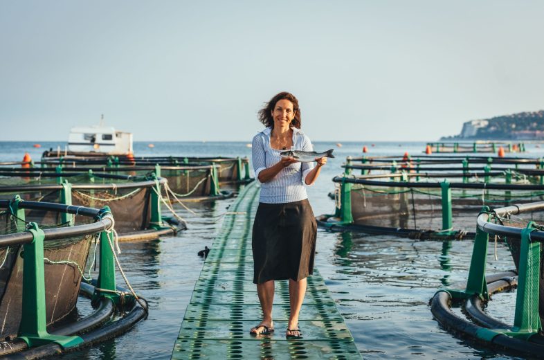 Morje, gospa na pomolu drži ribo